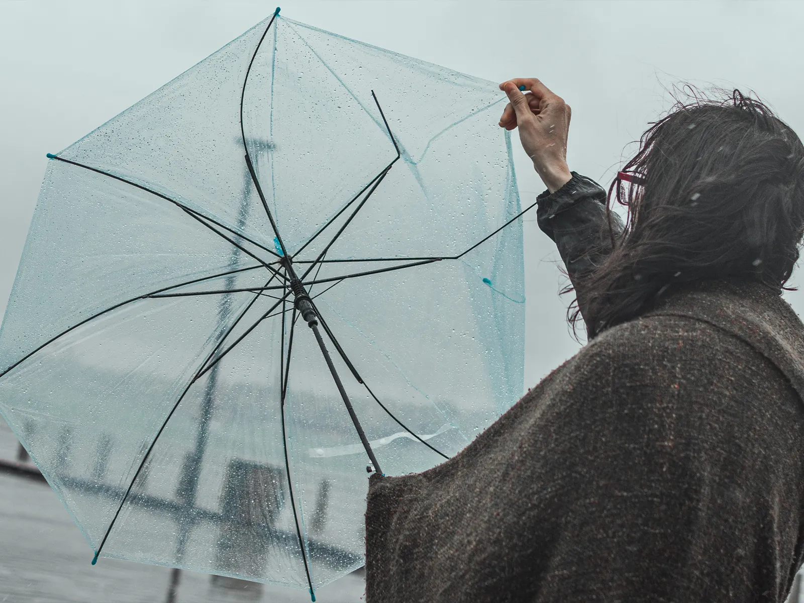 台風で傘が壊れた人のイメージ
